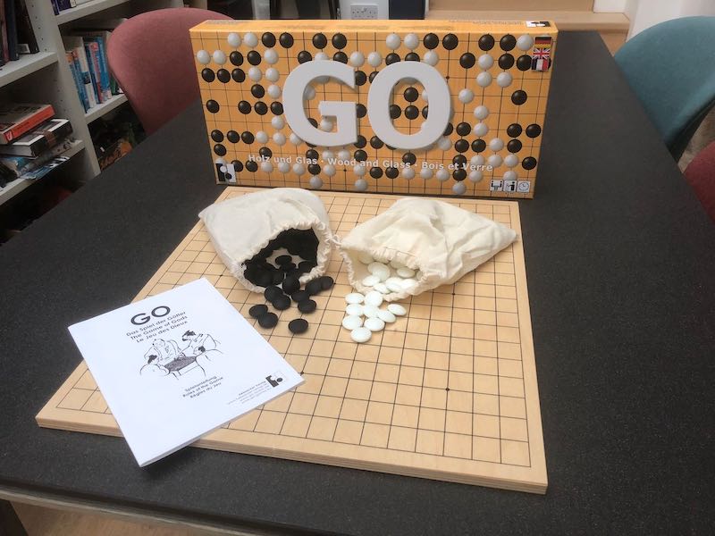 Basic Go Set, with stones, bags, rulebook sitting on top of board in front of box