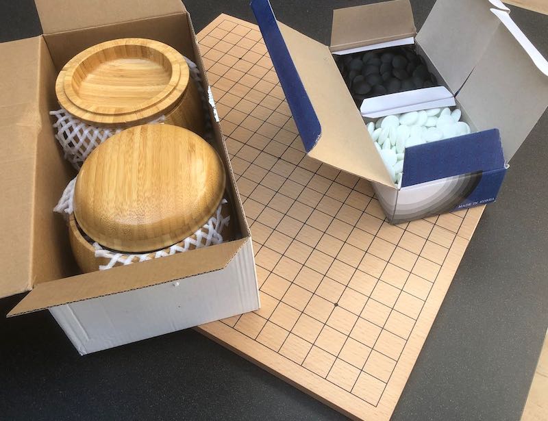Tournament Go set with bamboo bowls and stones in boxes sitting on board